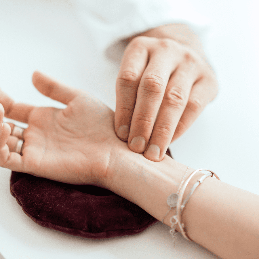 A close-up photo of an acupuncture practitioner's hand holding a needle next to a patient's hand.