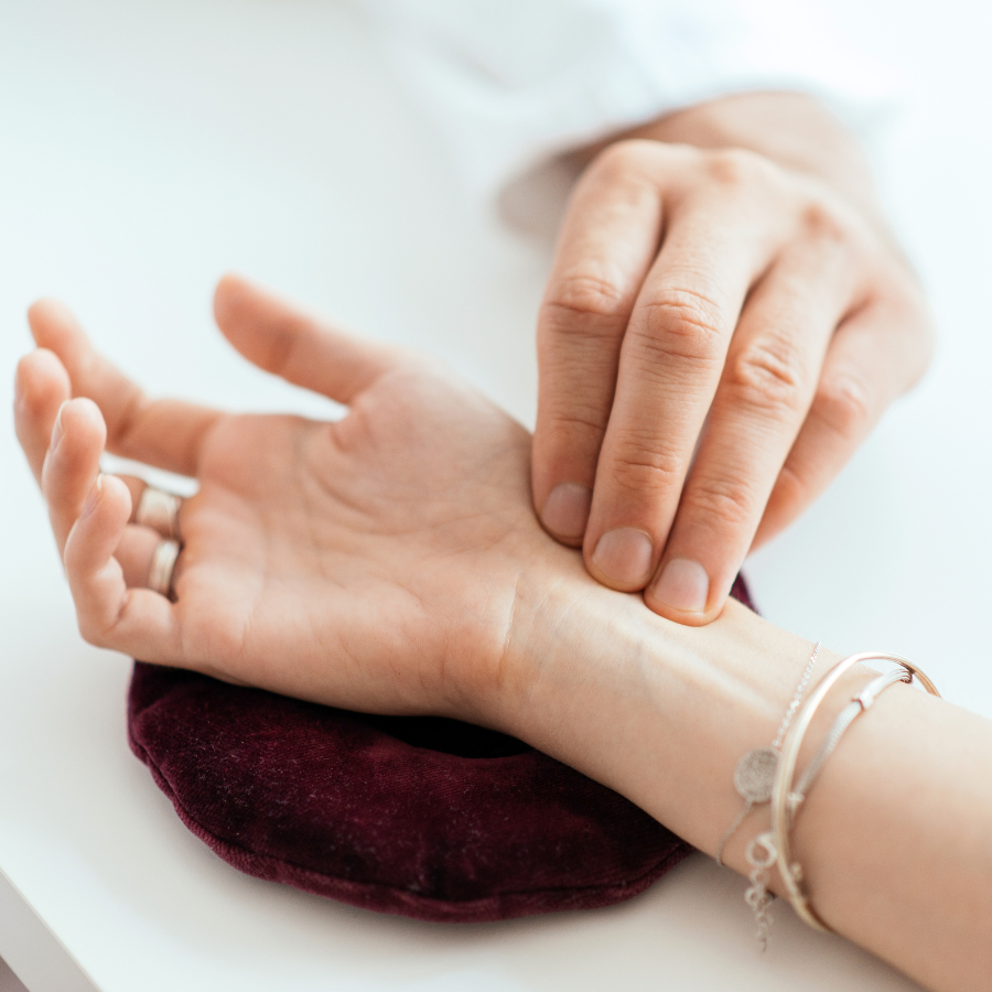 A close-up photo of an acupuncture practitioner's hand holding a needle next to a patient's hand.